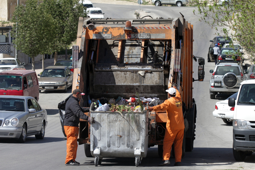 Sanitation workers empty a garbage container in Amman on Monday (Photo by Osama Aqarbeh)